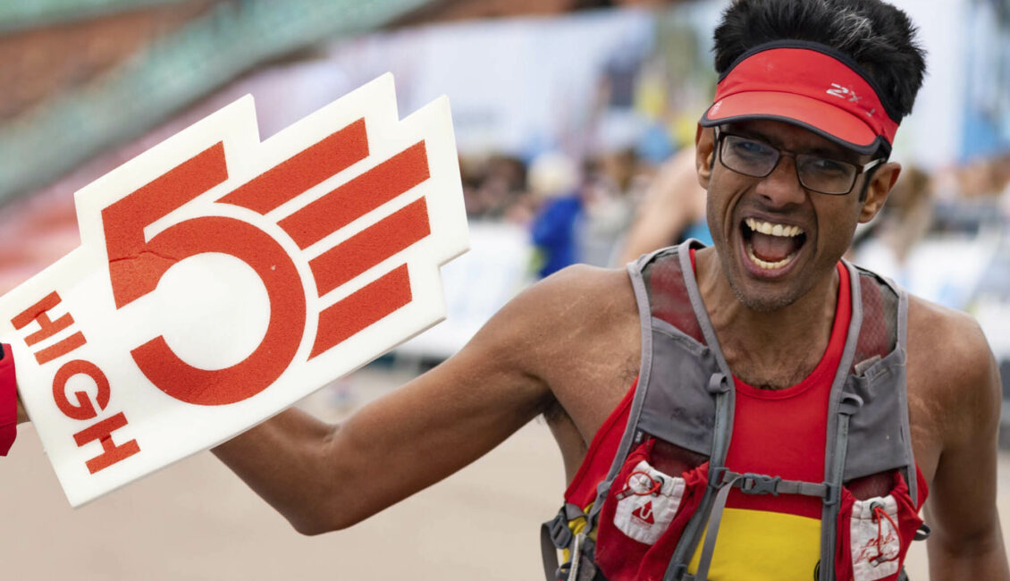 Runner high-fiving someone with a foam hand on.