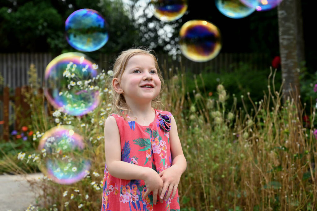 Little girl surrounded by bubbles.