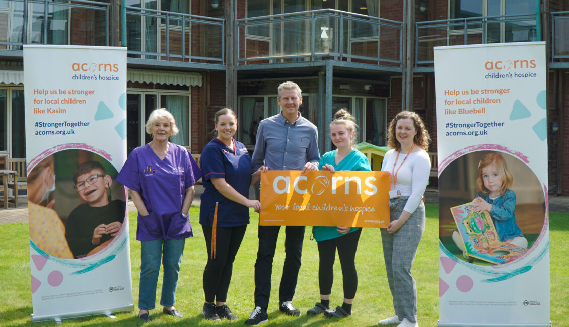 Five people standing next to pop up signs for Acorns Hospice.