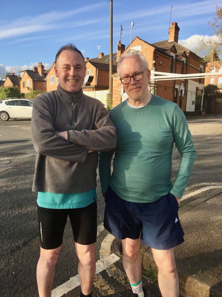 Two men standing together in running kit.